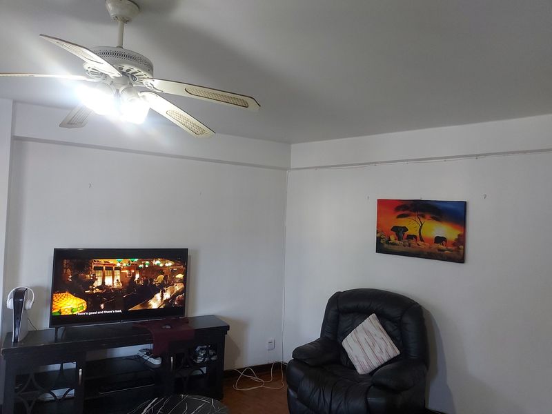 A living room area featuring a ceiling fan and neutral wall finishes, providing a functional space for relaxation.