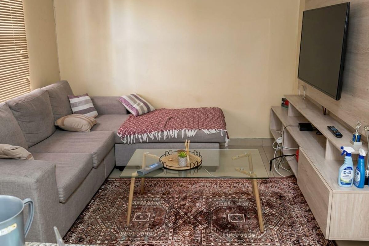 A cozy living room featuring a built-in media unit and venetian blinds, providing a functional and comfortable space for relaxation.