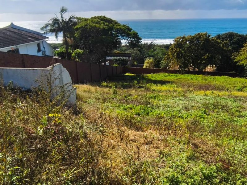 Vacant residential land featuring a sloping plot with established boundary walls and scenic ocean views.