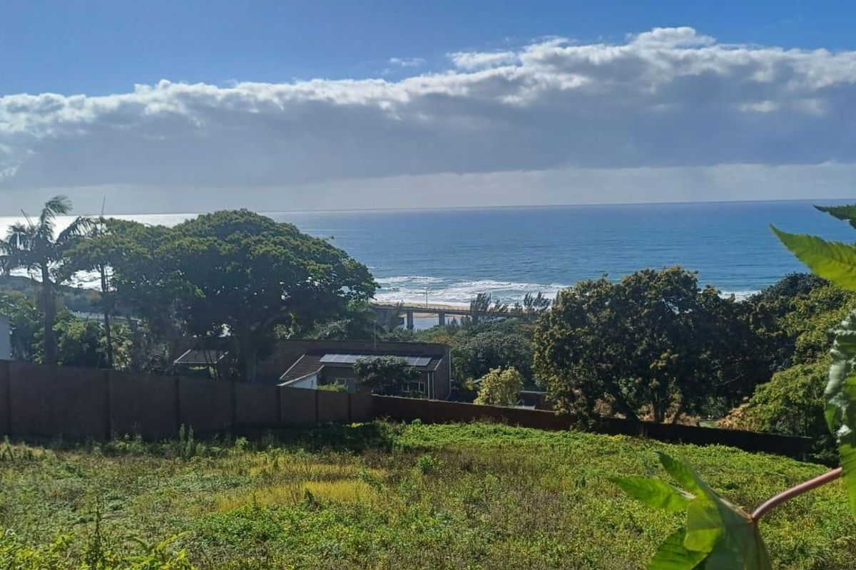 A scenic view of the ocean and coastline from the vacant residential property, featuring established trees and a boundary wall.