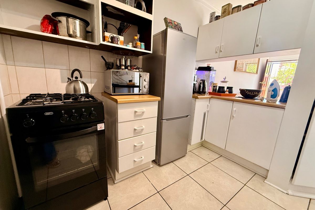 Compact kitchen featuring white cabinetry, wooden countertops, tiled flooring, and a built-in gas stove with oven.