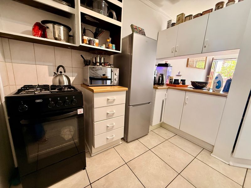 Compact kitchen featuring white cabinetry, wooden countertops, tiled flooring, and a built-in gas stove with oven.