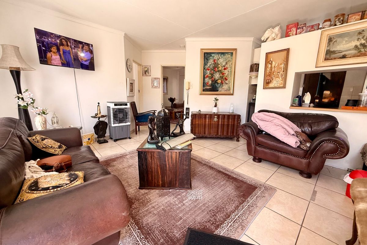 A living room featuring ceramic floor tiles and a convenient pass-through window connecting to the kitchen area.