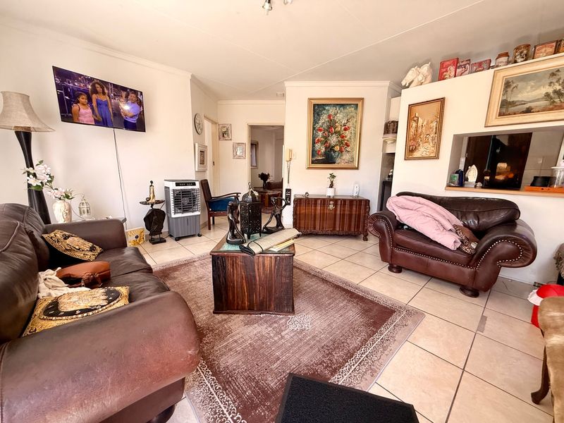 A living room featuring ceramic floor tiles and a convenient pass-through window connecting to the kitchen area.
