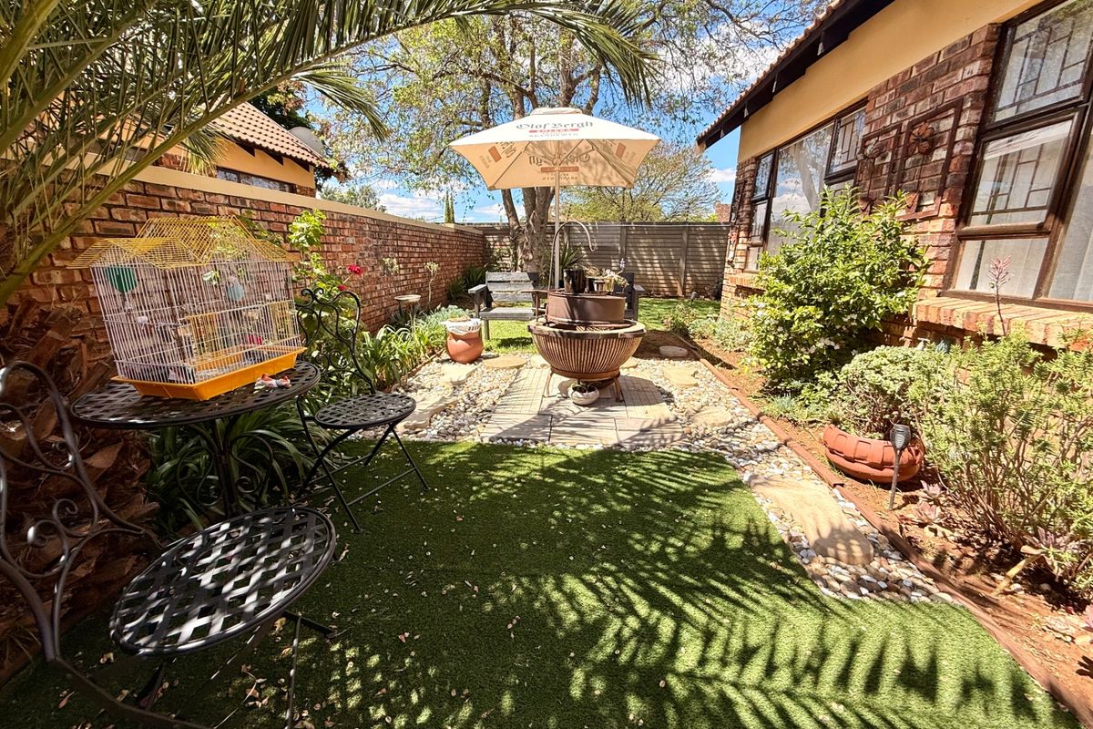 A private rear garden featuring a paved patio area, artificial lawn, and face brick boundary walls, providing a low-maintenance outdoor living space.