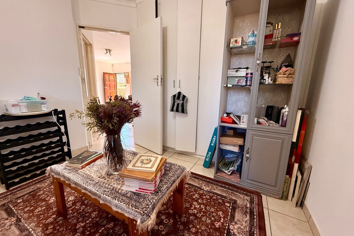A bedroom featuring built-in cupboards and tiled flooring, with a view through to an adjacent room.