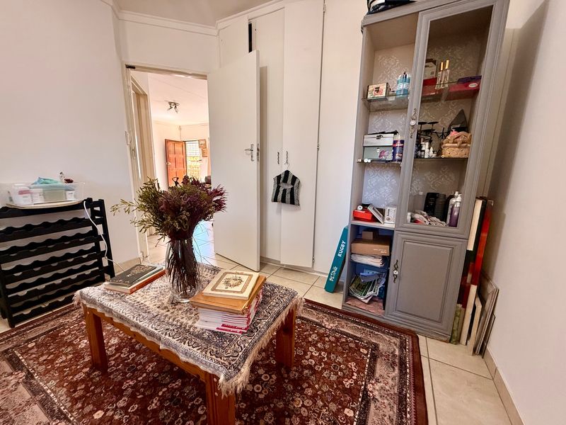 A bedroom featuring built-in cupboards and tiled flooring, with a view through to an adjacent room.