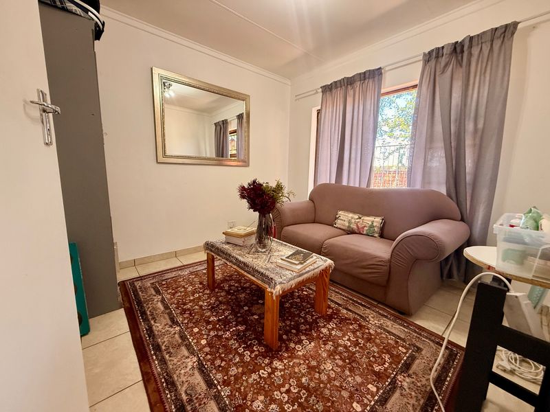 A cozy living room featuring neutral tiled flooring and classic cove cornicing, providing a functional and comfortable space.