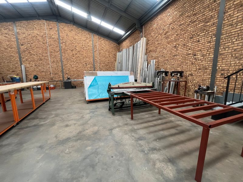 Spacious industrial utility area featuring exposed brick walls, concrete flooring, and high-clearance steel roof trusses with integrated skylights.