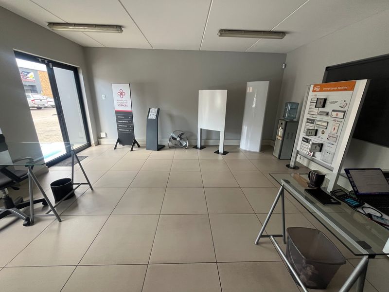 A functional office space featuring tiled flooring, drop ceilings, and natural light access through a glass door, suitable for professional use.