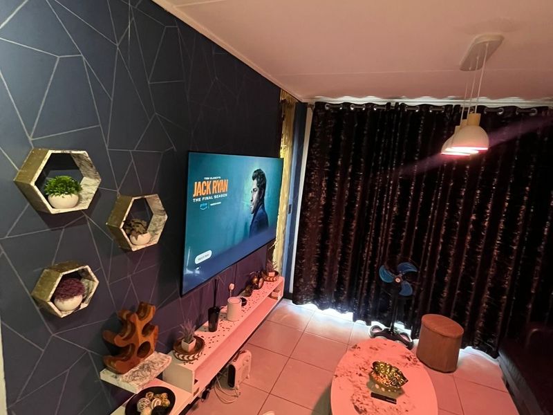 A living room featuring a geometric patterned feature wall, tiled flooring, and modern pendant lighting.