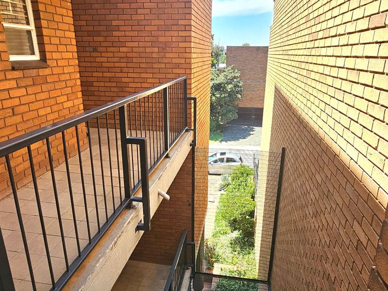 View of the apartment building exterior showing brick facade, metal balustrades, and tiled walkways between building blocks.