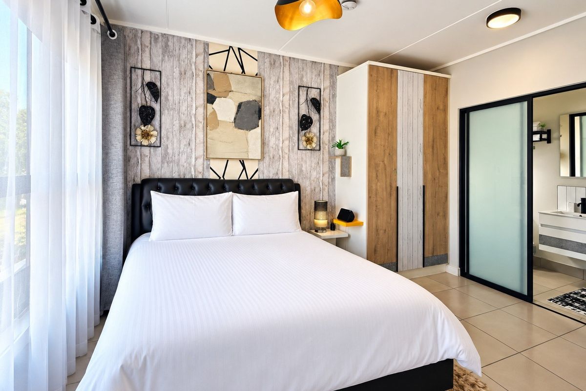 A well-maintained bedroom featuring tiled flooring, a built-in wardrobe, and an en-suite bathroom access through a modern sliding door.