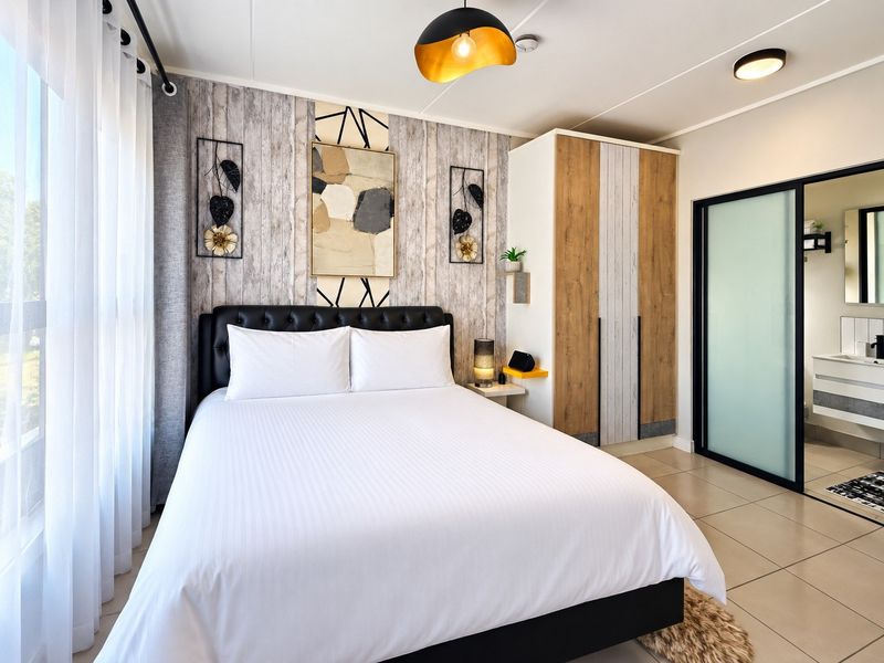 A well-maintained bedroom featuring tiled flooring, a built-in wardrobe, and an en-suite bathroom access through a modern sliding door.
