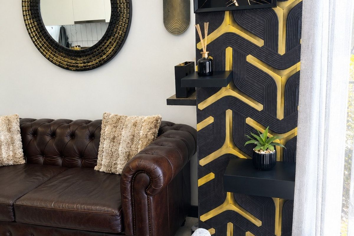 A well-maintained living room featuring a striking black and gold geometric accent wall and tiled flooring.