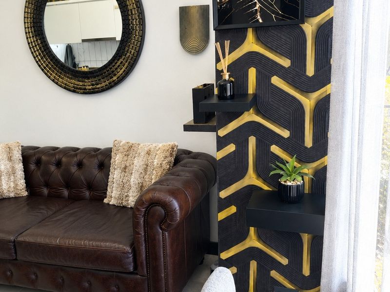 A well-maintained living room featuring a striking black and gold geometric accent wall and tiled flooring.