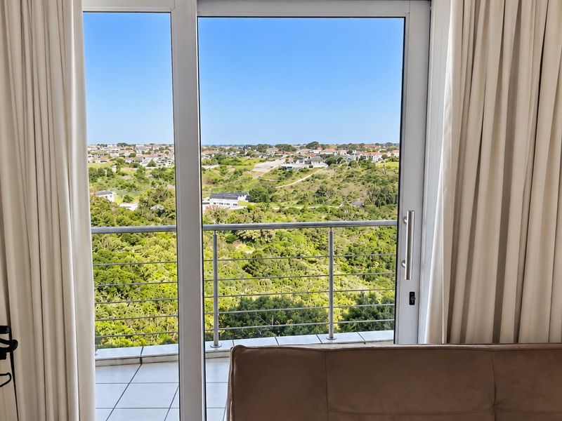 A view from an interior room through a sliding glass door onto a balcony overlooking a scenic landscape.