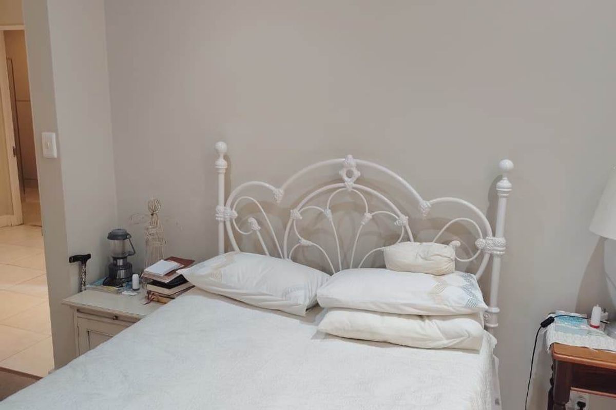 A standard bedroom featuring neutral wall tones, carpeted flooring, and a visible hairline crack on the upper wall section.