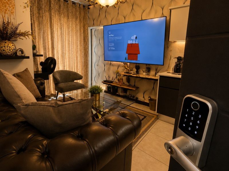 Compact open-plan living area featuring tiled floors, decorative wallpaper, and a modern digital keypad entry system.