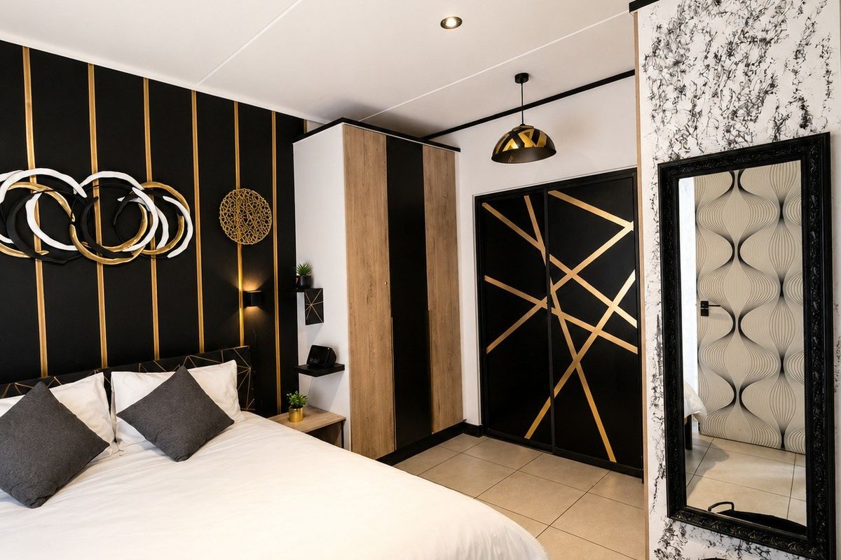 Modern bedroom featuring a stylish black and gold feature wall, built-in wardrobe, tiled flooring, and contemporary track lighting.