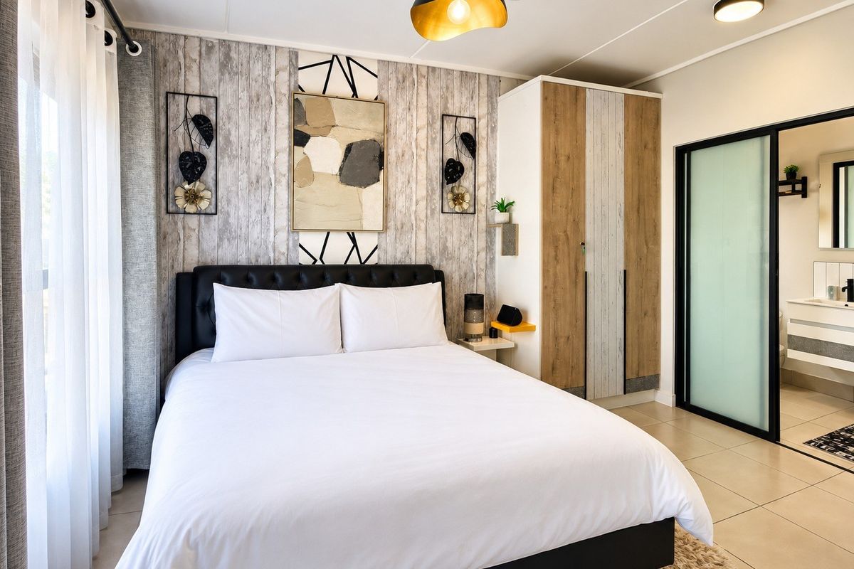 A well-maintained bedroom featuring a built-in wardrobe, tiled flooring, and an adjoining bathroom accessible via a modern sliding door.