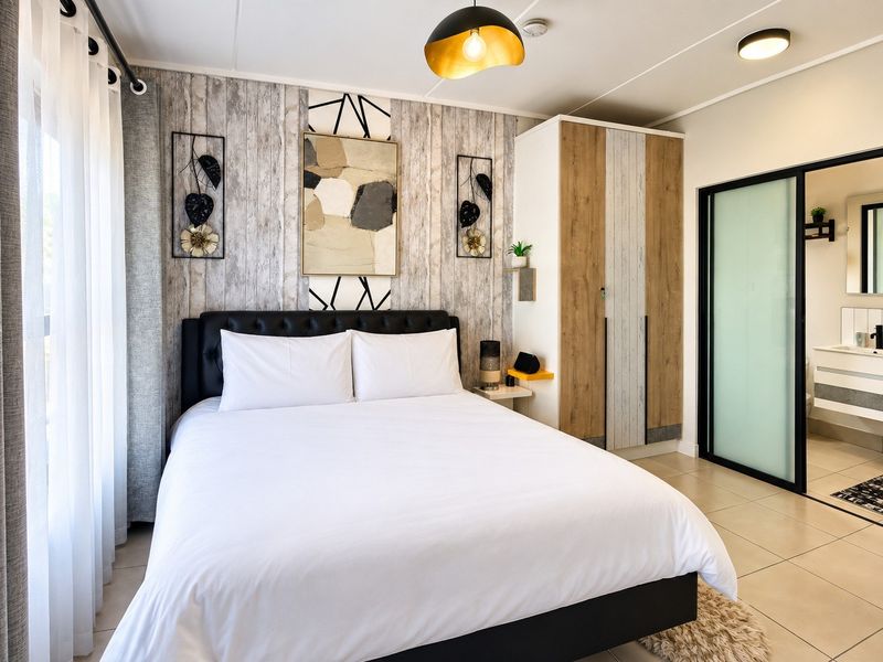 A well-maintained bedroom featuring a built-in wardrobe, tiled flooring, and an adjoining bathroom accessible via a modern sliding door.