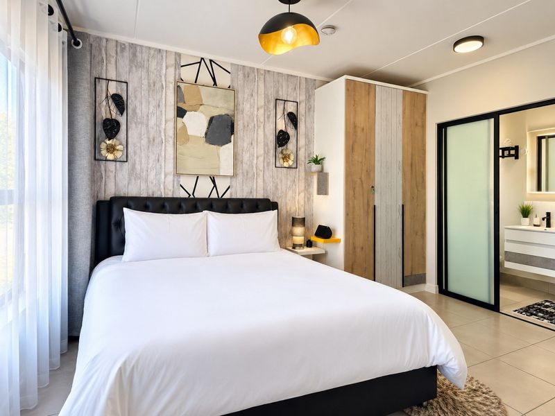 Modern bedroom featuring a built-in wardrobe, tiled flooring, and an integrated en-suite bathroom with a sliding glass door.