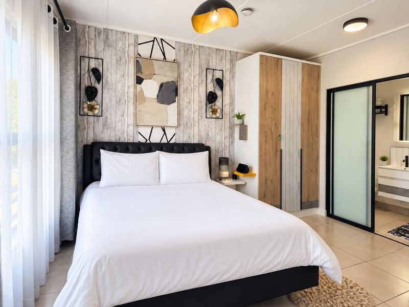 A well-maintained bedroom featuring built-in wardrobes, tiled flooring, and an en-suite bathroom accessible via a sliding door.