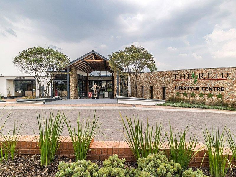 The front elevation of The Reid Lifestyle Centre, featuring modern stone cladding, timber roof detailing, and a paved entrance area.