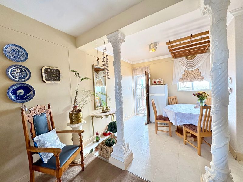 Open plan living and dining area featuring decorative columns, tiled flooring, and a ceiling-mounted drying rack, providing a functional and traditional layout.