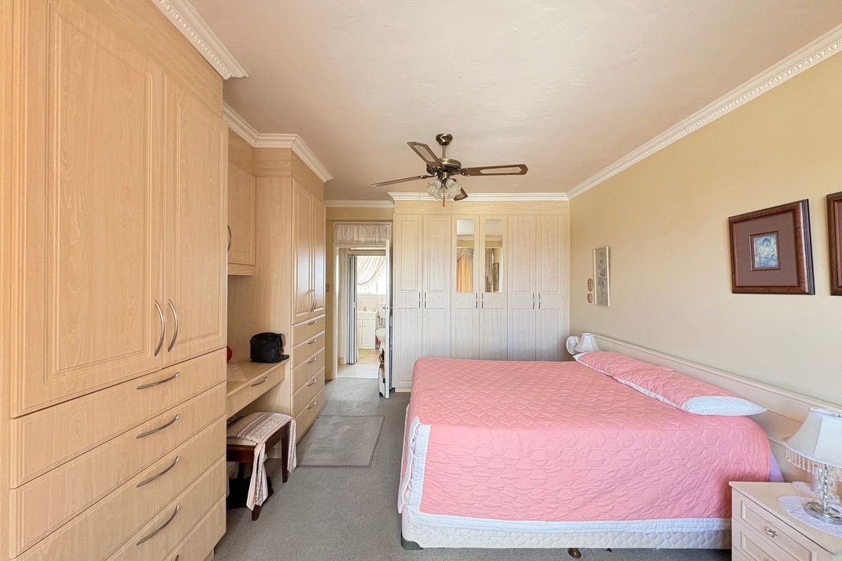 Spacious bedroom featuring extensive built-in cabinetry, crown molding, and a ceiling fan, offering ample storage and a functional layout.