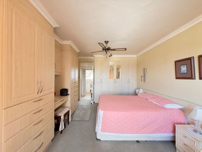 Spacious bedroom featuring extensive built-in cabinetry, crown molding, and a ceiling fan, offering ample storage and a functional layout.
