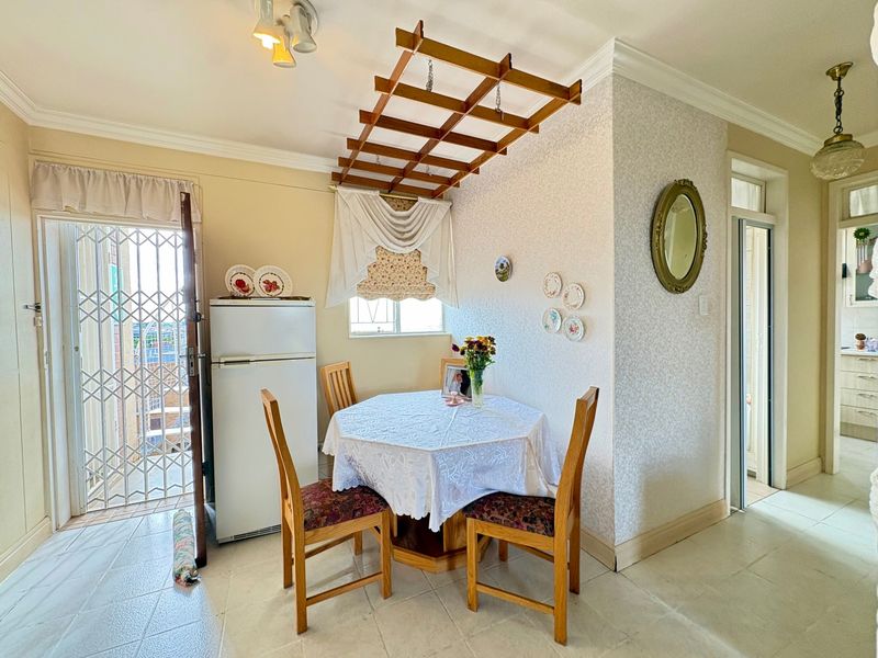 Dining area featuring tiled flooring, decorative cornicing, and a ceiling-mounted drying rack, with direct access to an exterior security gate.