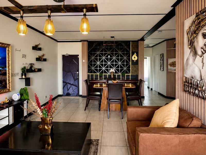 A well-maintained open-plan living and dining area featuring modern tiled floors, decorative wall paneling, and stylish pendant lighting.