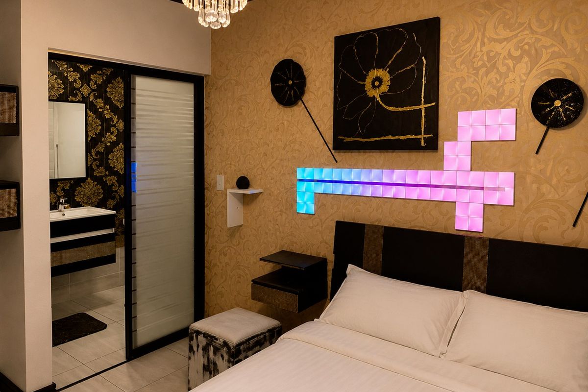 A well-maintained bedroom featuring an en-suite bathroom with a modern vanity, sliding glass door, and decorative wall lighting.