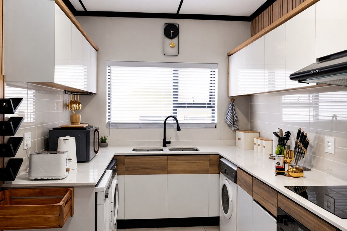 Modern, well-appointed kitchen featuring sleek white and wood-tone cabinetry, quartz countertops, integrated appliances, and a functional double-basin sink with a contemporary mixer tap.