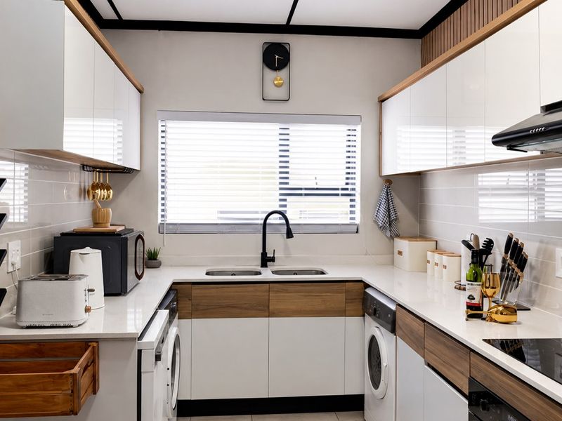Modern, well-appointed kitchen featuring sleek white and wood-tone cabinetry, quartz countertops, integrated appliances, and a functional double-basin sink with a contemporary mixer tap.