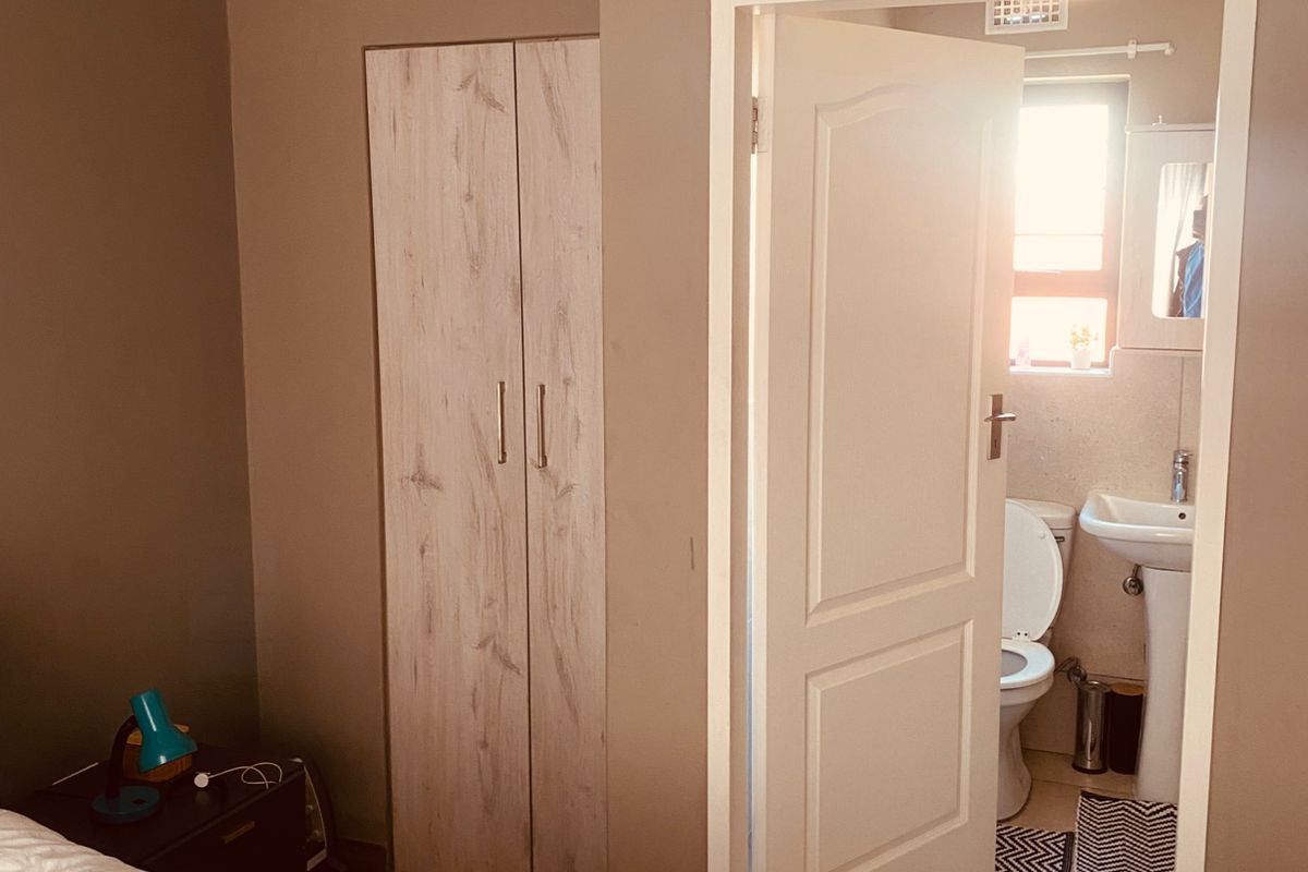 A bedroom featuring built-in wardrobes and crown molding, with an adjoining en-suite bathroom equipped with a pedestal basin and toilet.