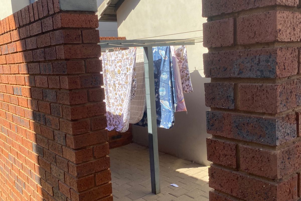 A private rear courtyard area featuring brick boundary walls and paved flooring, currently utilized as a utility space with a fixed washing line.