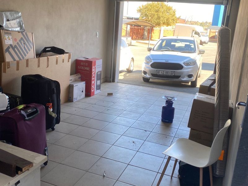 A functional garage space featuring tiled flooring and an automated garage door mechanism, currently used for storage.