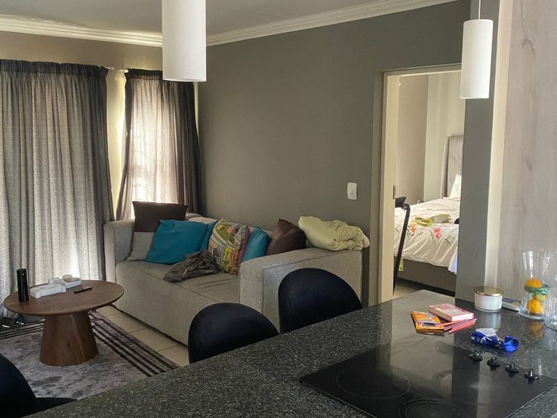 Open plan living area featuring a kitchen with granite countertops and electric hob, flowing into a lounge space with access to a balcony.