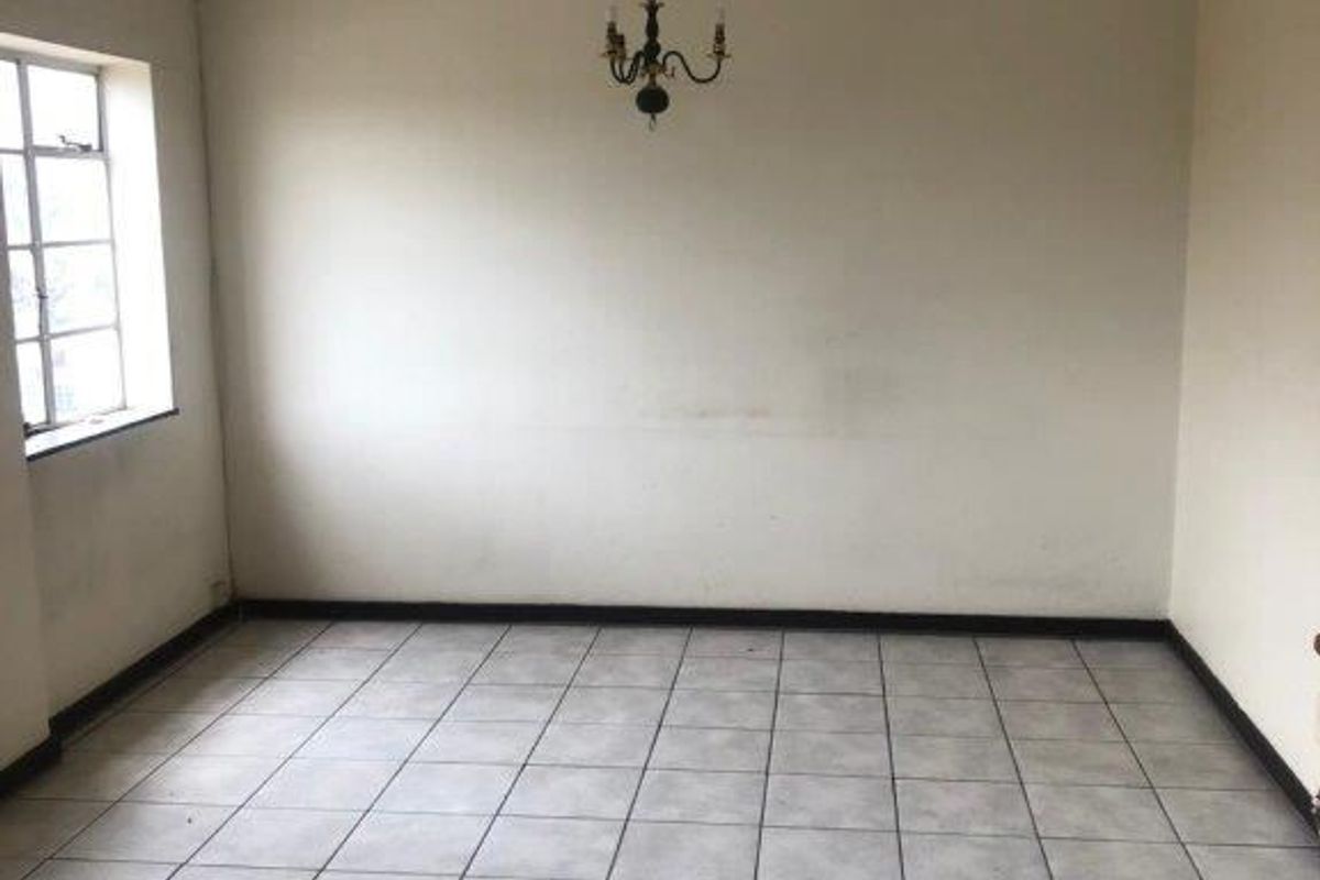 An empty living room featuring tiled flooring, neutral walls, and a ceiling-mounted light fixture, offering a blank canvas for personalization.