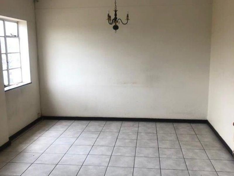 An empty living room featuring tiled flooring, neutral walls, and a ceiling-mounted light fixture, offering a blank canvas for personalization.