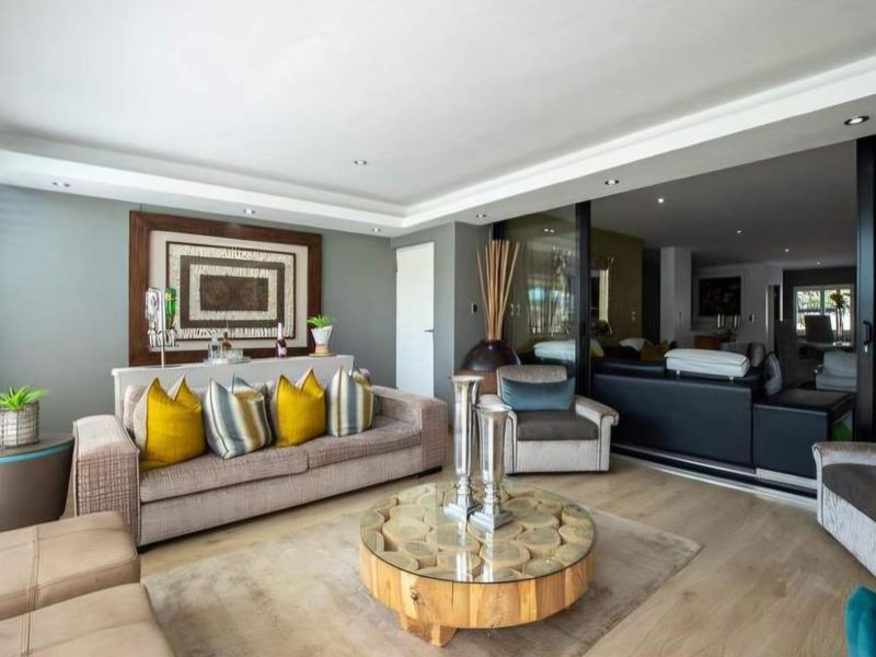 A spacious living room featuring modern laminate flooring, recessed ceiling lighting, and large sliding glass doors that provide seamless access to the outdoor area.