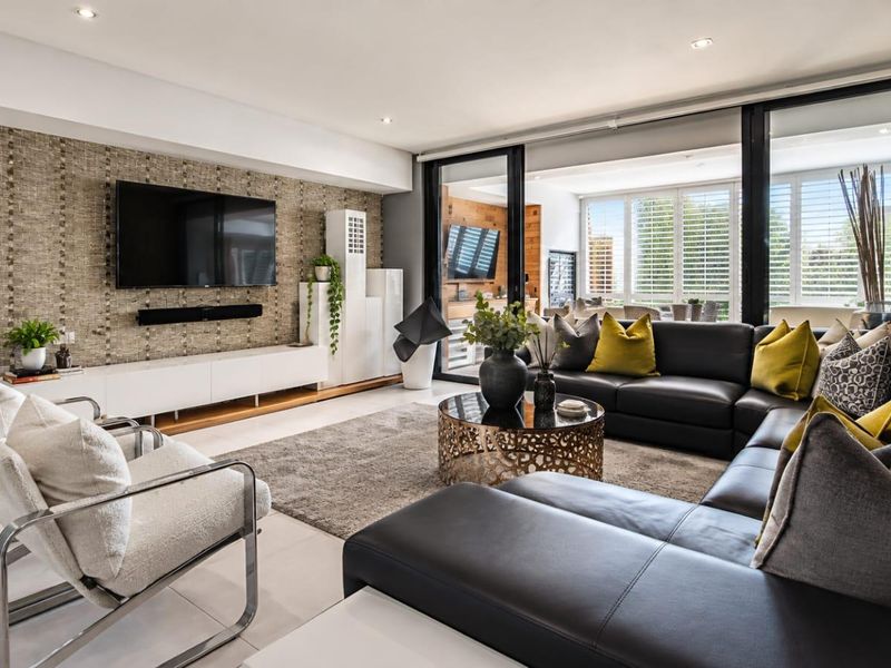 Modern living room featuring a textured feature wall, recessed lighting, and large sliding glass doors that open to an outdoor patio area.