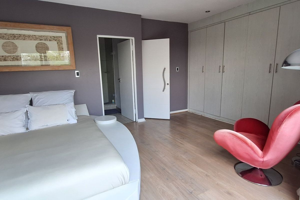 Spacious bedroom featuring laminate flooring, extensive built-in cupboards, and direct access to an en-suite bathroom.