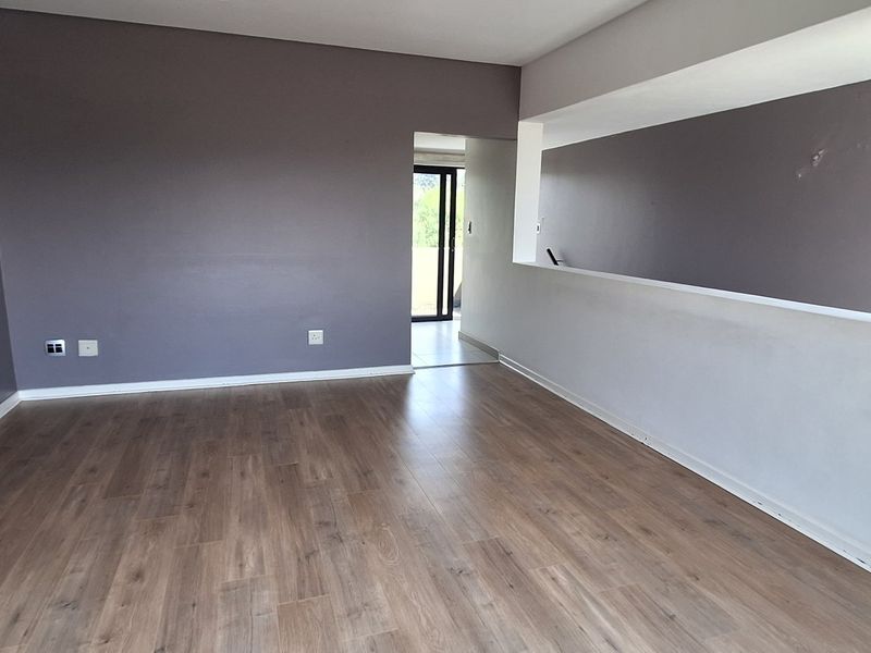An empty living room featuring laminate flooring and a recessed wall niche, offering a blank canvas for interior design.