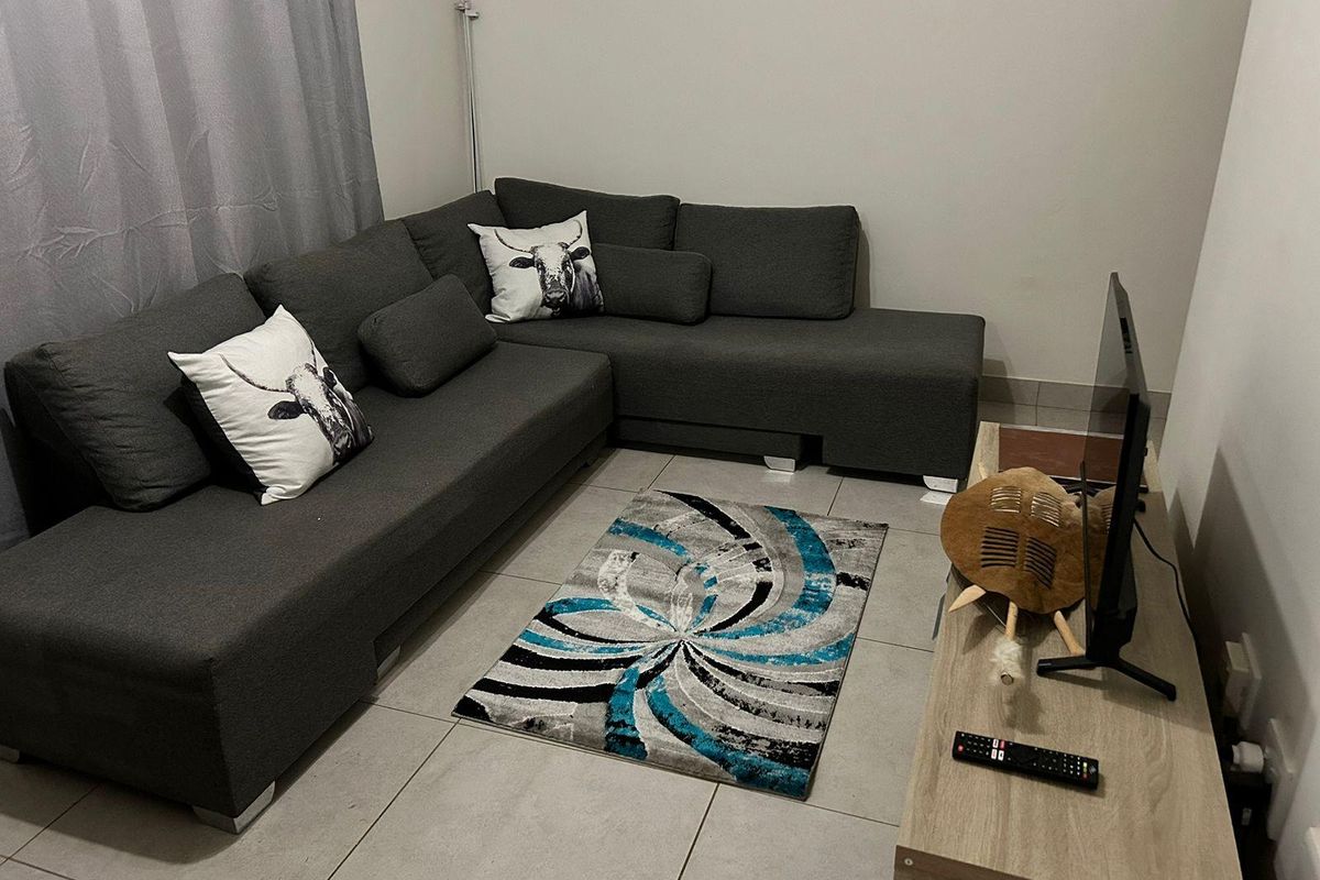 A compact living room featuring neutral tiled flooring and plain walls, providing a functional space for relaxation.