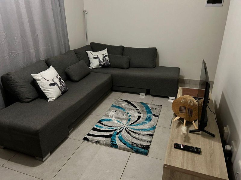 A compact living room featuring neutral tiled flooring and plain walls, providing a functional space for relaxation.