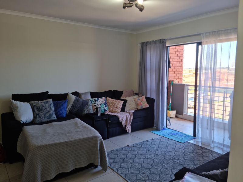 A living room area featuring tiled flooring and a sliding glass door providing access to an outdoor balcony space.
